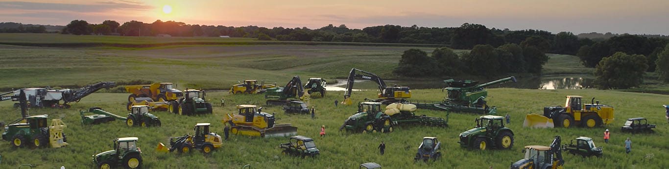 Mennesker som går gjennom ulike typer John Deere-utstyr i en stor åker.