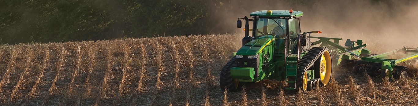 En sporet John Deere-traktor beveger seg gjennom en allerede høstet åker