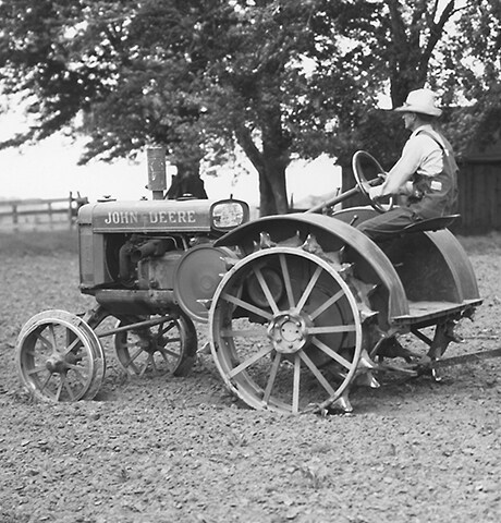 Historisk "GP"-traktor fra John Deere for generell bruk drar en roterende hakke nr. 7fra John Deere på en åker