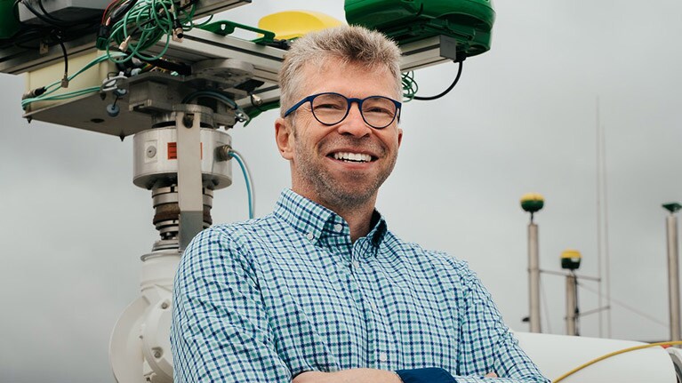 Georg Kormann ved siden av en robotarm.