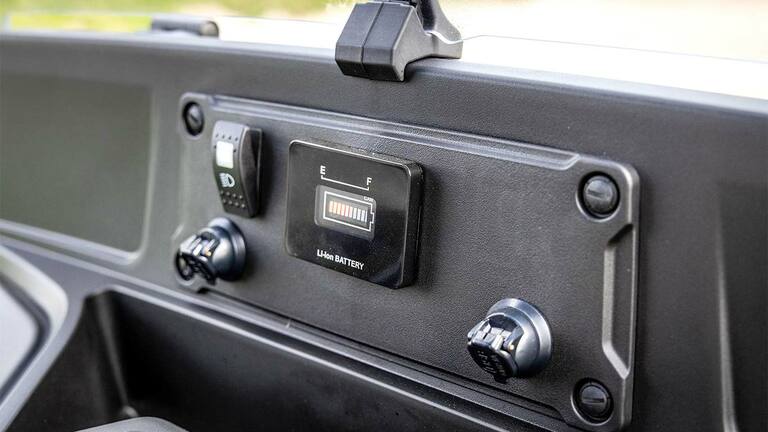 Instrumentpanel for en John Deere Gator GS elektrisk modell som viser batterinivåindikator og strømporter.