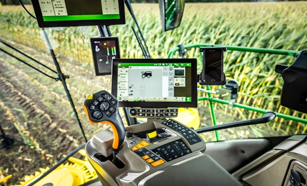 Selvgående fôrhøster F9 700 som laster en Joskin-tilhenger trukket av en 6R John Deere-traktor