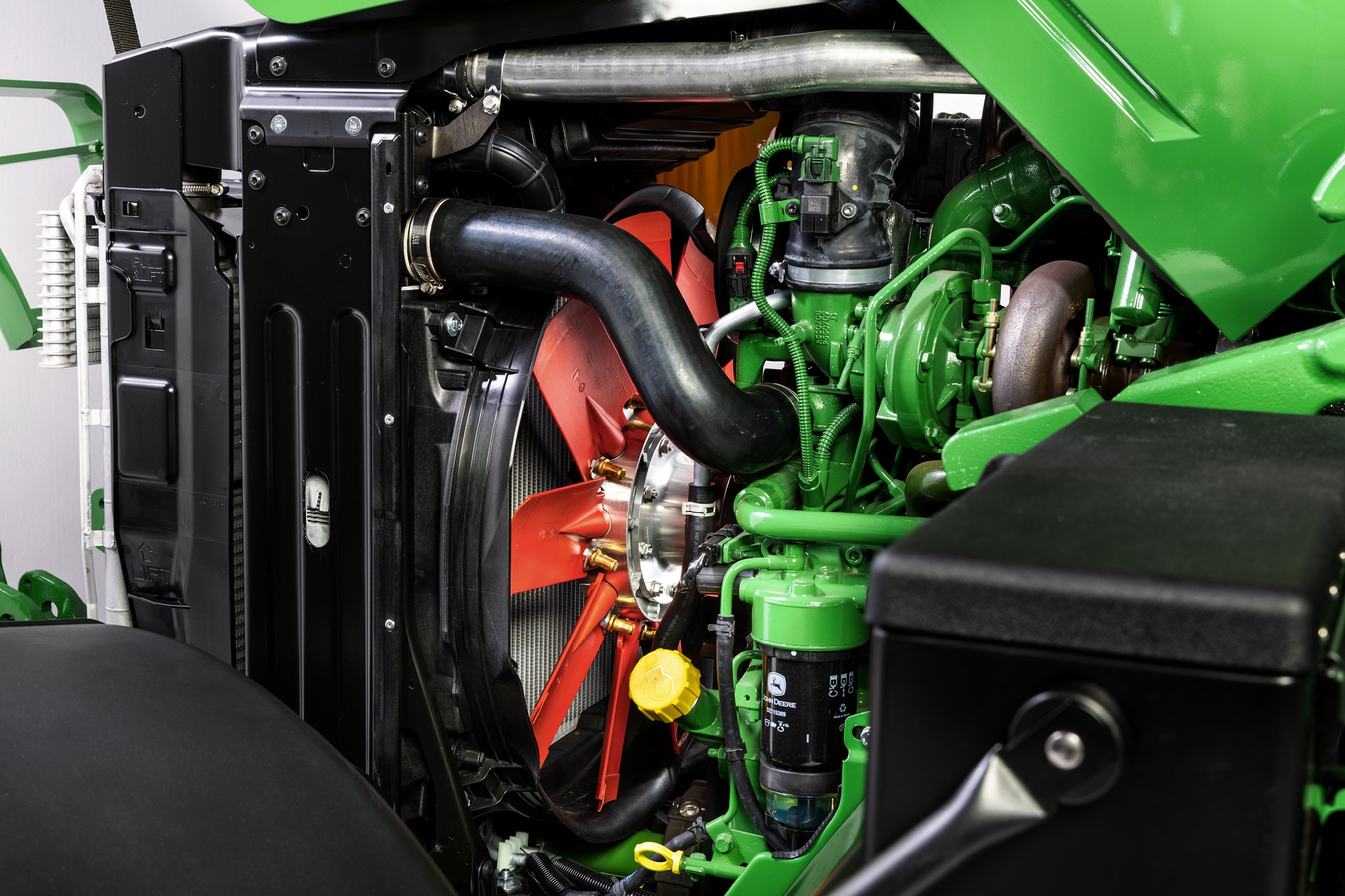 Nærbilde av motorrommet til John Deere 6M-serien som fremhever kjølesystemet og motorkomponenter.