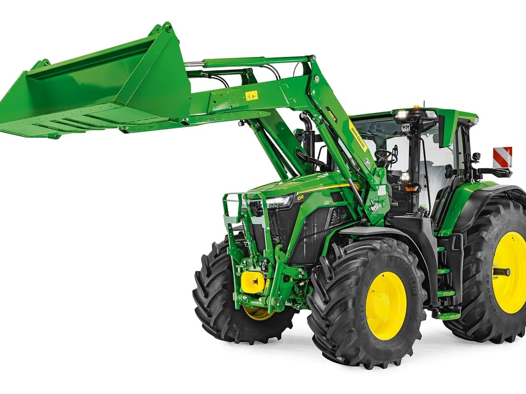 John Deere-traktor med frontlaster senket og skuffe festet, isolert på hvit bakgrunn.
