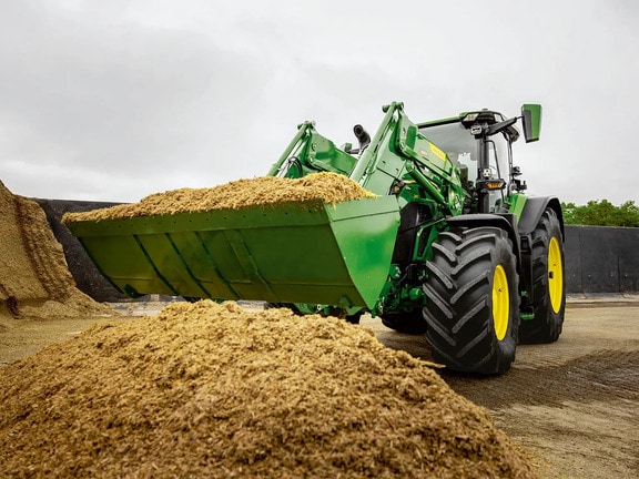 John Deere-traktor bruker frontlaster til å frakte kuttet silofôr i et lagringsområde for landbruket.