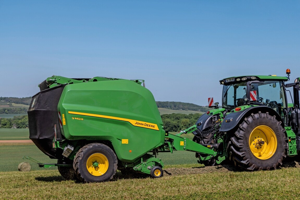 John Deere V462R trukket av en John Deere 6R 185-traktor for rundballepressing av høy